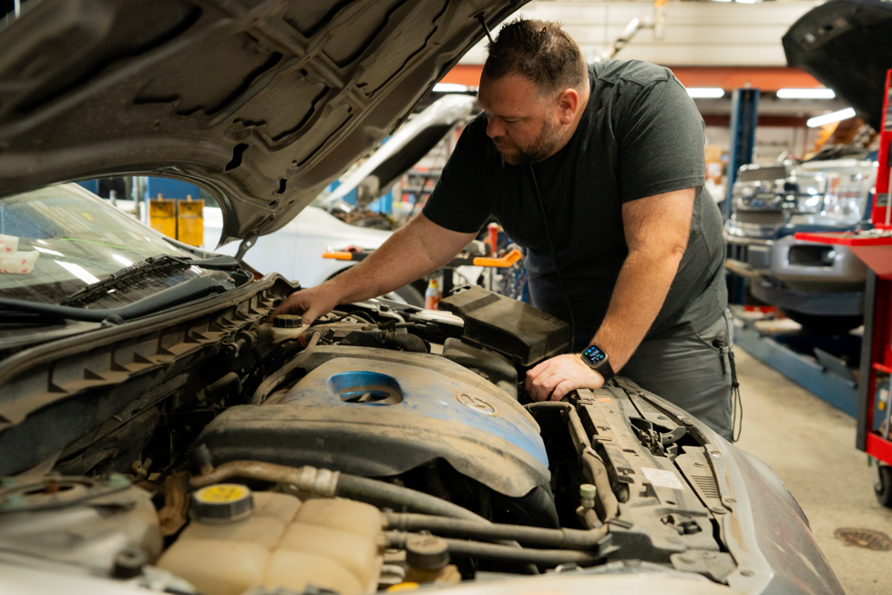 Independent auto repair shop technician inspecting a vehicle engine